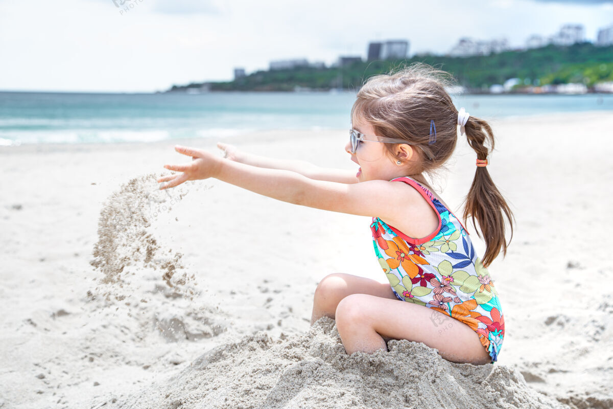 童年小孩子在海边抛掷沙子夏日娱乐和消遣休息玩坐