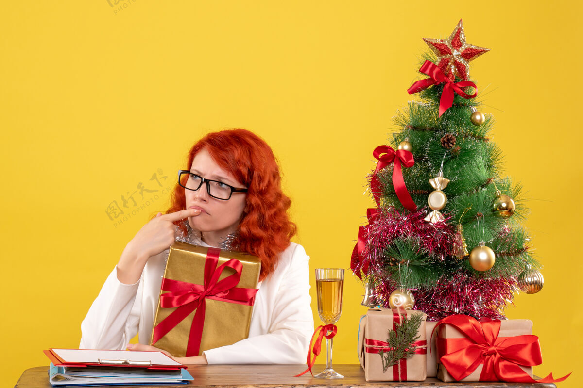 前面前视图女医生坐在黄色背景上与圣诞礼物情感圣诞节快乐