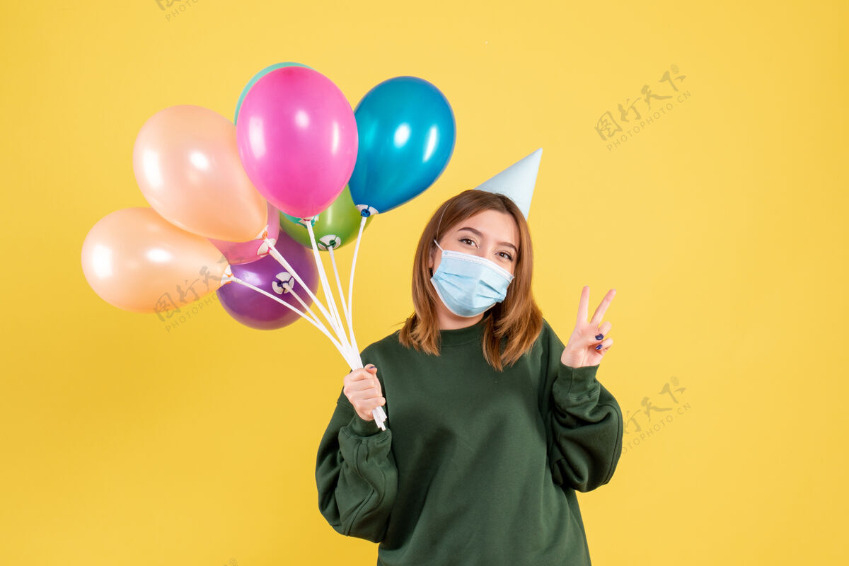 气球正面图戴面具的年轻女性手持五颜六色的气球生日人Covid