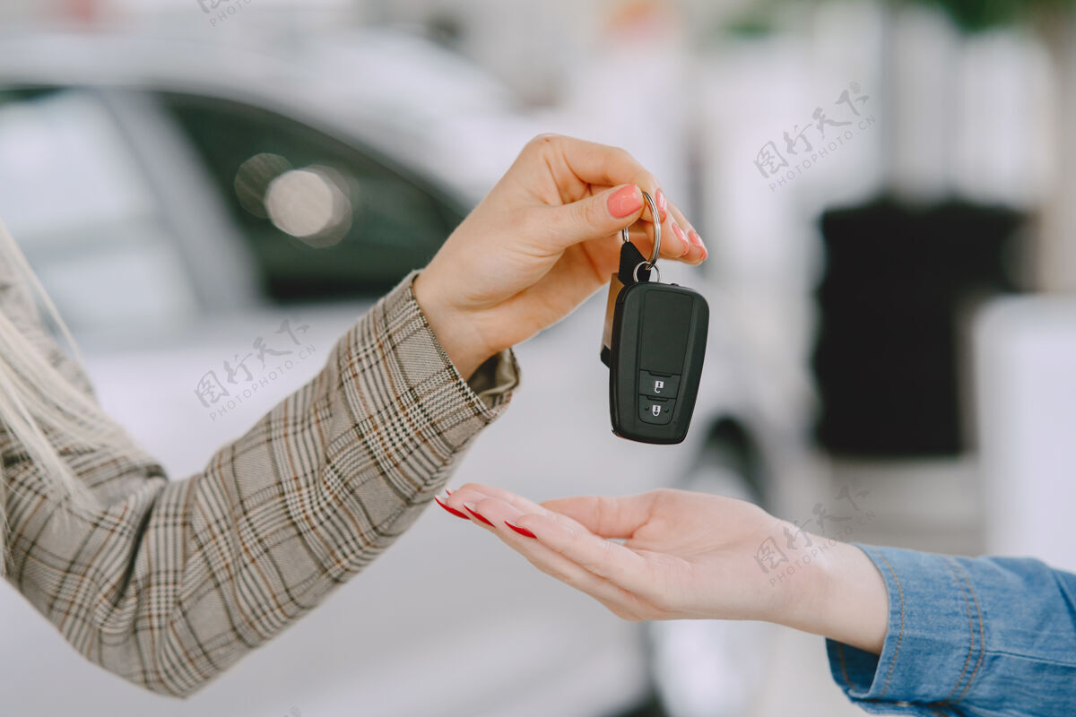 展示汽车沙龙里的女士买车的女士穿着蓝色裙子的优雅女士经理给客户钥匙快乐运输室内