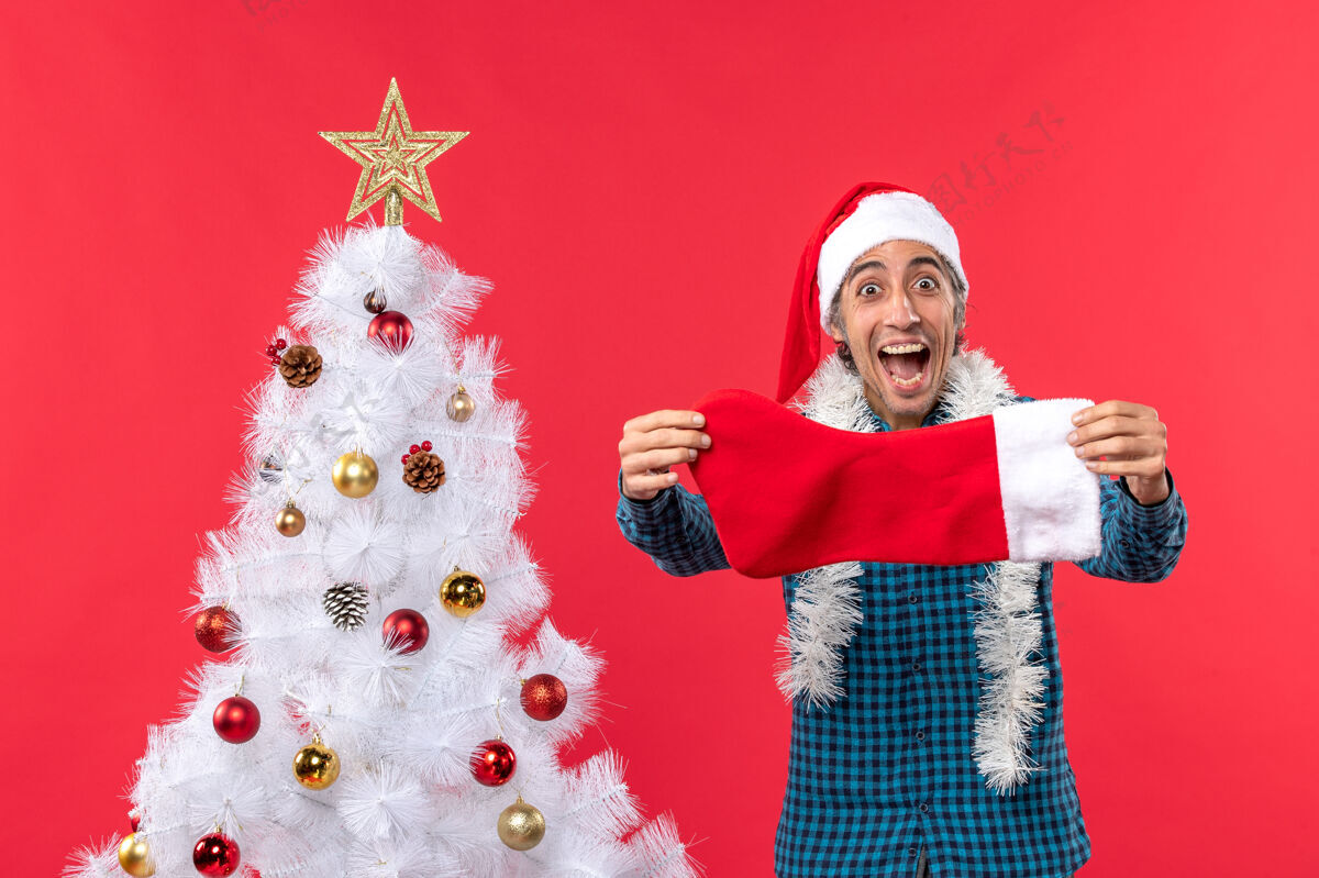 圣诞老人兴奋极了 情绪激动的年轻人 戴着圣诞老人帽 穿着蓝色条纹衬衫 手里拿着圣诞袜子庆祝兴奋圣诞老人