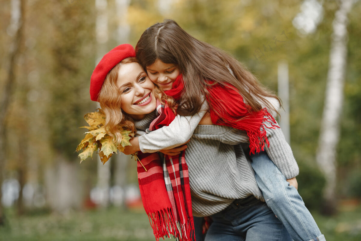 家庭时髦的母亲带着女儿黄色的秋天戴着红领巾的女人毛衣自然秋天