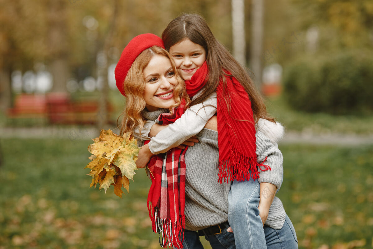休闲时髦的母亲带着女儿黄色的秋天戴着红领巾的女人户外金发户外