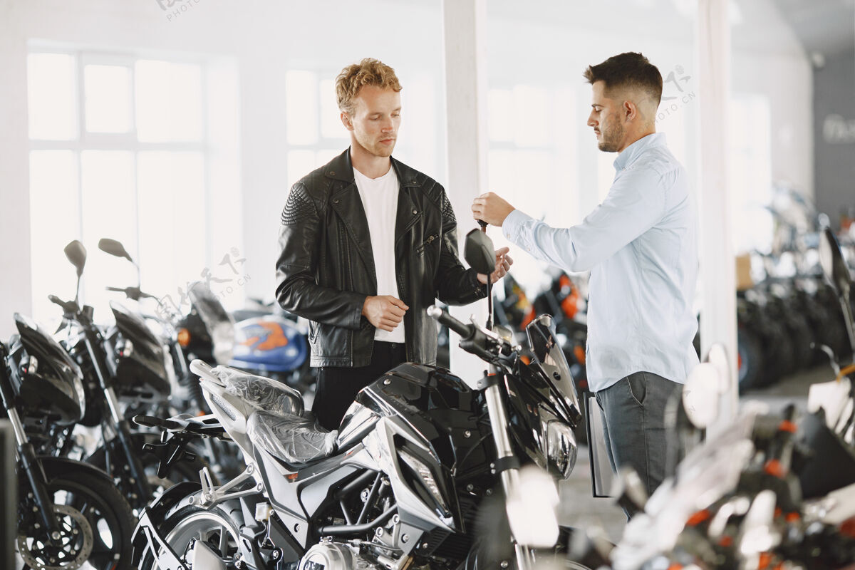 运输男人在摩托店里选摩托车穿黑色夹克的家伙经理和客户在一起摩托车手阳刚经销商