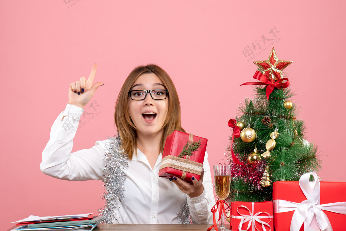 圣诞节女工正坐在粉红色的椅子上 手里拿着圣诞礼物礼物办公桌女性工人