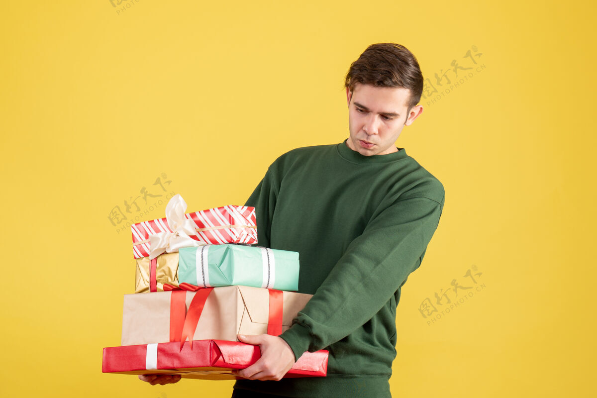 毛衣正面图穿着绿色毛衣的疲惫男人拿着黄色的礼物漂亮人抱着