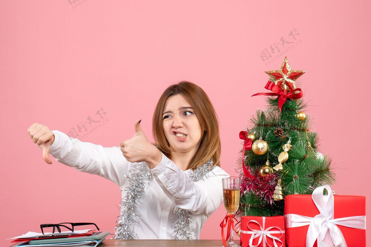 女工人坐在粉红色桌子后面的女工人的正视图工人花圣诞节