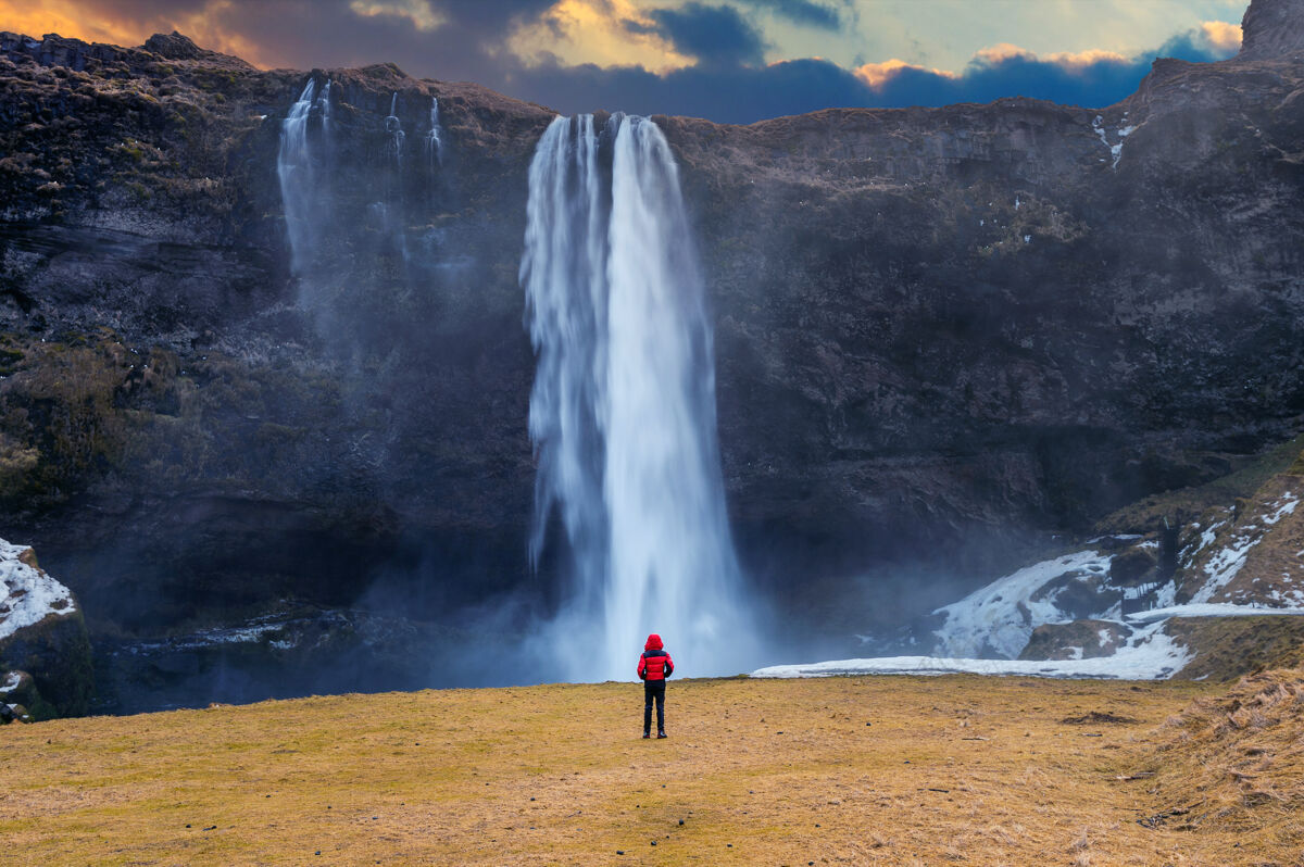 瀑布冰岛的塞尔加兰兹瀑布穿红色夹克的家伙看着塞尔加兰兹瀑布冬天目的地美丽