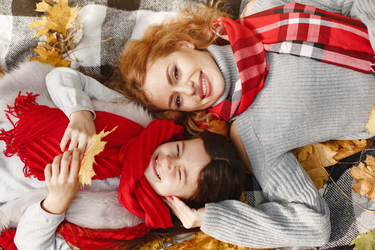 妈妈时髦的母亲带着女儿黄色的秋天戴着红领巾的女人金发坐着肖像