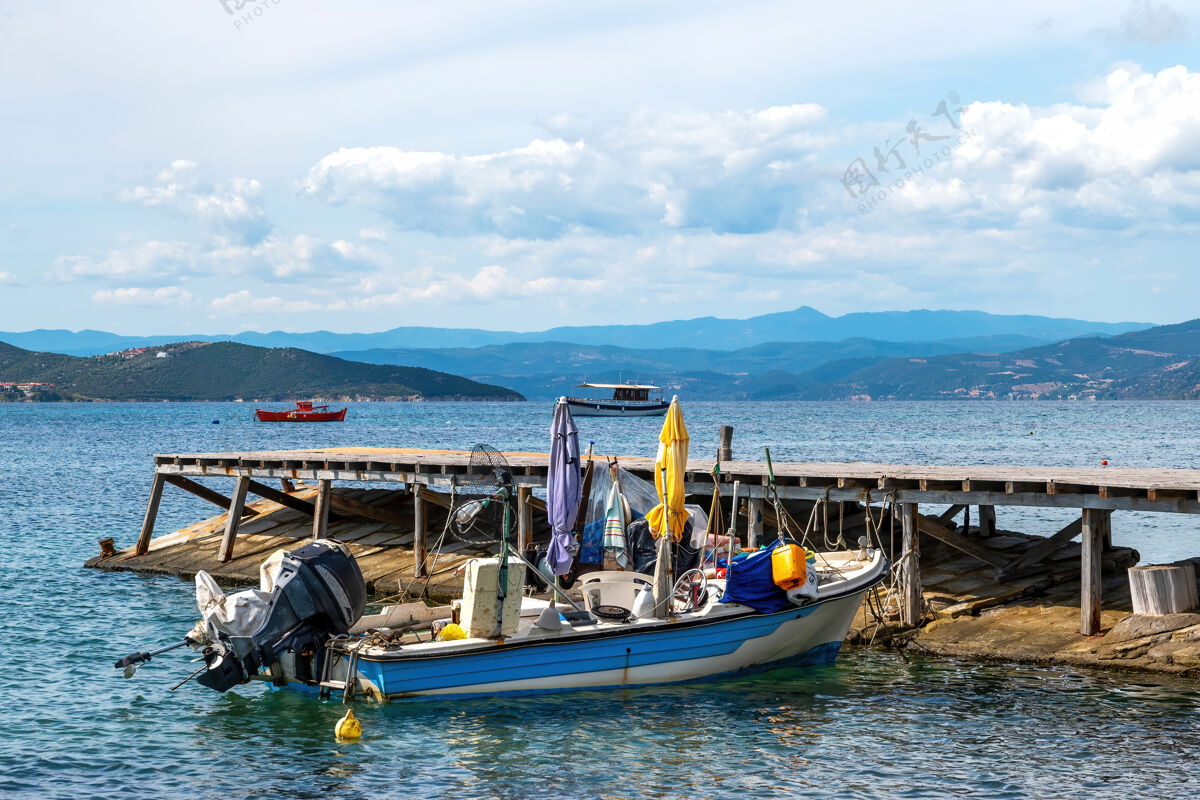 地平线在爱琴海的一个码头上搁浅的金属摩托彩色船成本 丘陵和乌拉努波利斯 希腊的一个城镇阳光度假房子