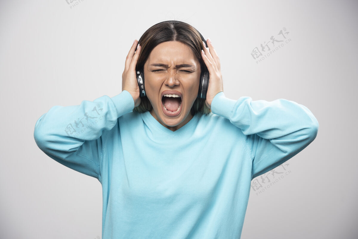 失望穿着蓝色运动衫的金发女孩听着耳机 却不喜欢音乐娱乐金发负面