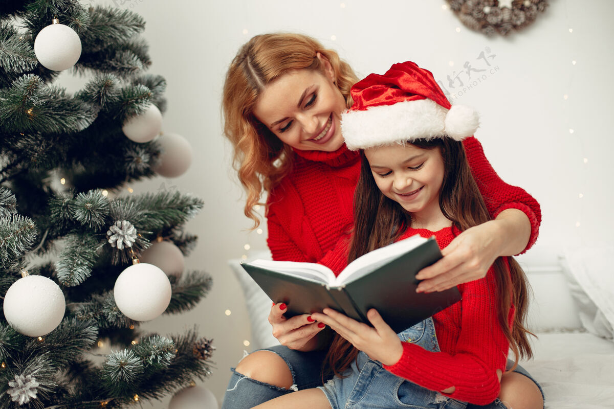 礼物人们在为圣诞节做准备母亲在和女儿玩耍一家人在节日的房间里休息孩子穿着红色毛衣圣诞老人女孩给