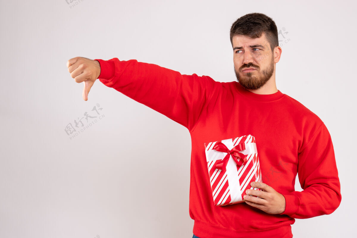 年轻身穿红衫的年轻人手持圣诞礼物站在白墙上的正视图年轻的男性情绪人