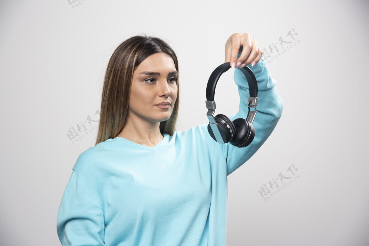音乐穿着蓝色运动衫的金发女孩拿着耳机 准备戴上耳机听音乐金发女年轻