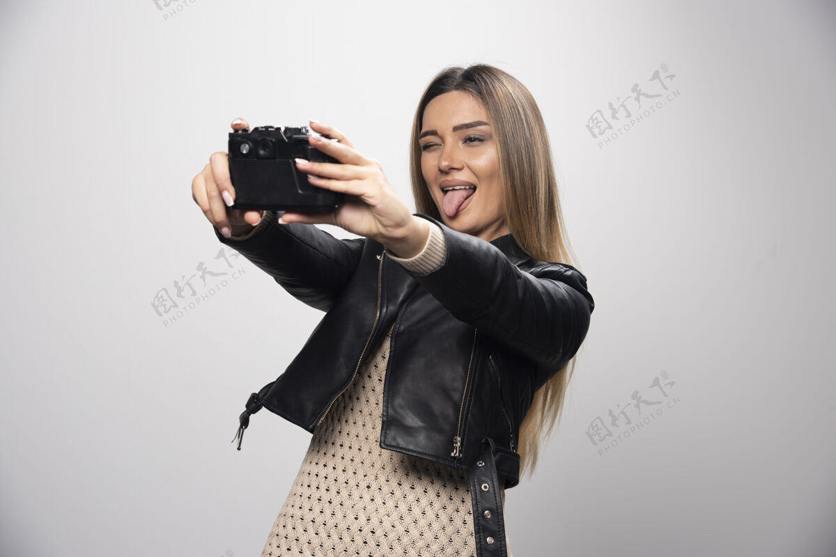 乐趣穿着黑色皮夹克的金发女孩拿着相机自拍年轻人人摄影