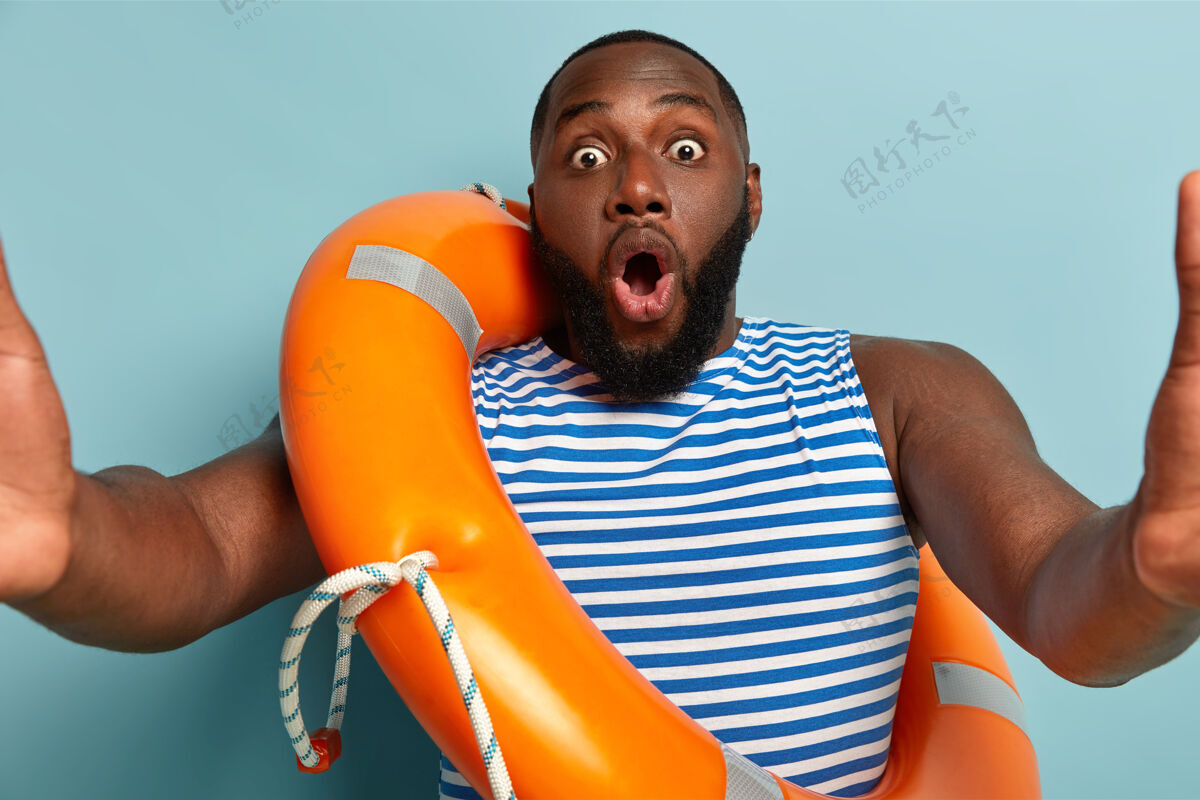 奇迹惊呆了的黑人男子摆着安全的漂浮物自拍 表情惊恐 眼睛被窃听 嘴巴张开情绪化水平反应