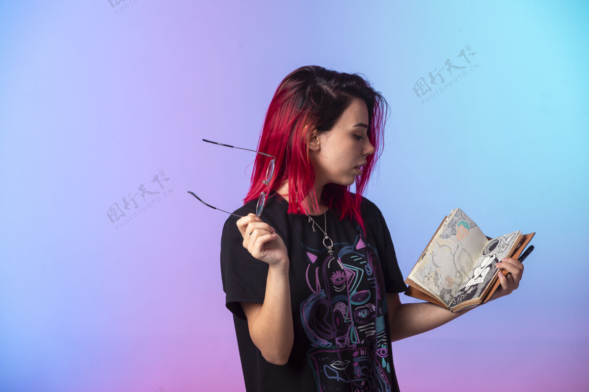 表情一个粉红色头发的年轻女孩拿着一本素描本在检查女性人类成人
