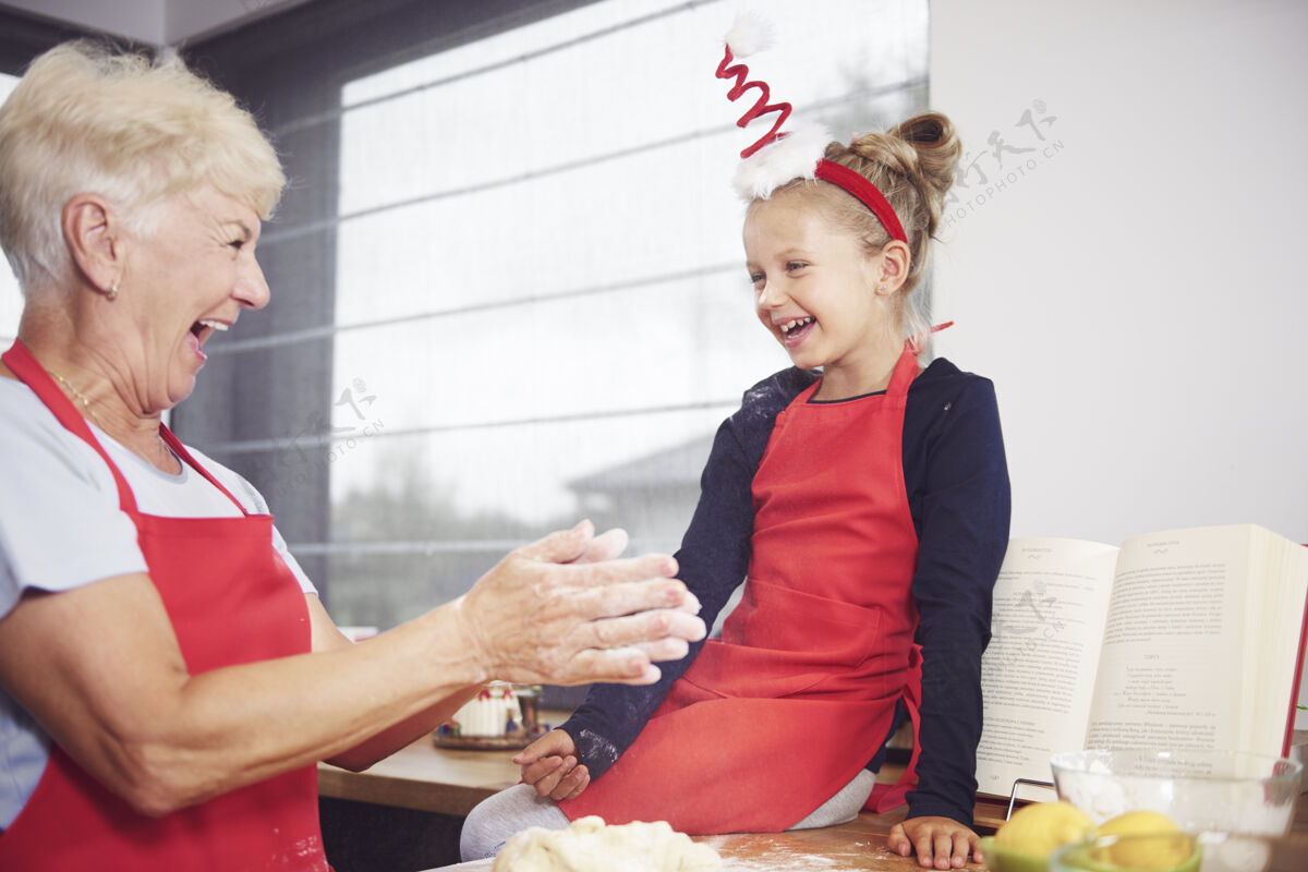 玩奶奶和女孩在厨房里玩做蛋糕烹饪向下
