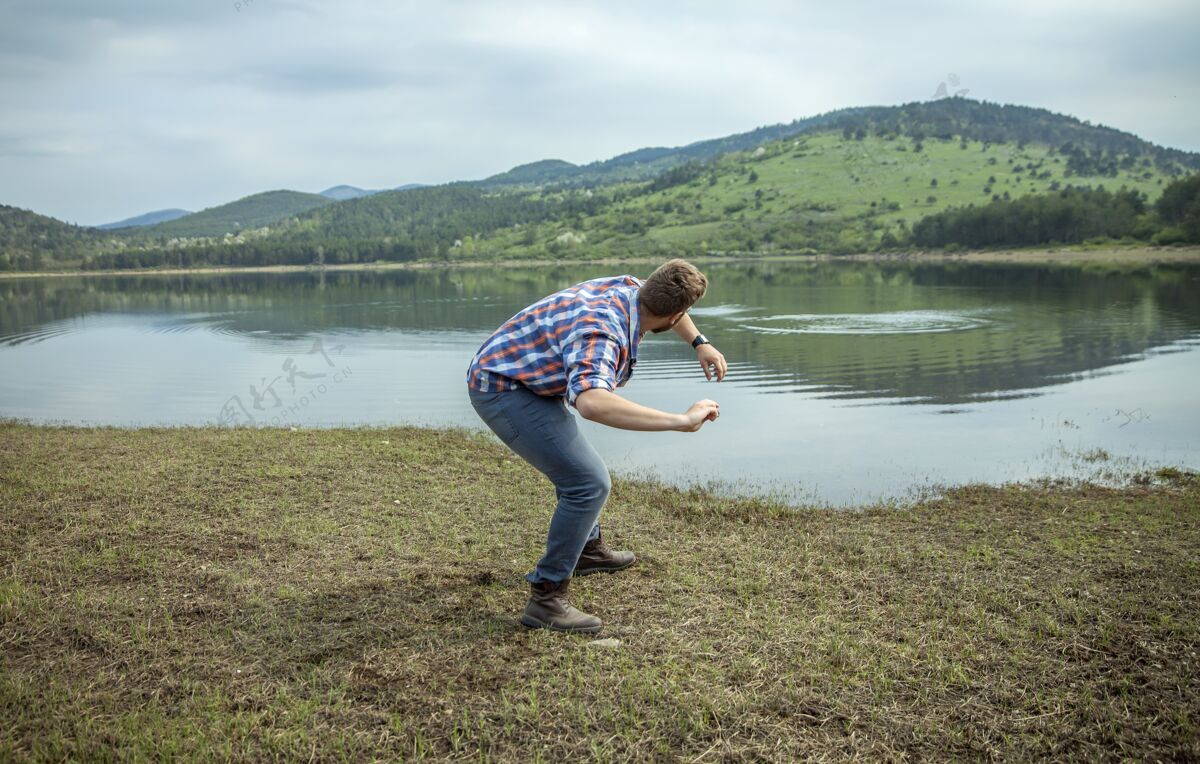 欢乐年轻人在湖水上跳石头放松投掷绿色
