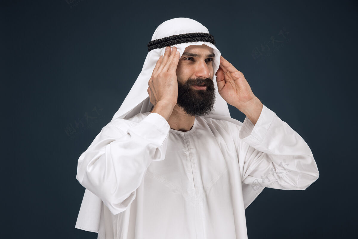阿拉伯深蓝色工作室背景的阿拉伯沙特男人惊讶东方沙特