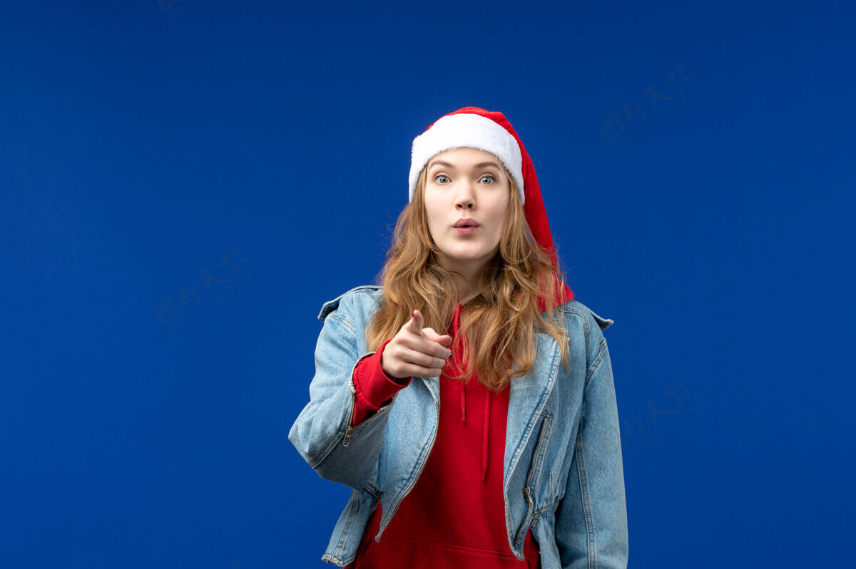 开朗正面图蓝色办公桌上戴着红色圣诞帽的年轻女性圣诞节情感假期桌子快乐成人