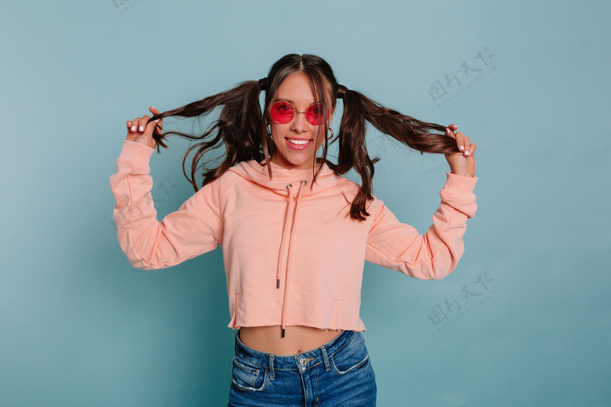 心情有趣迷人的女人 留着浓密的头发 穿着粉色套头衫 穿着休闲服 在蓝色的墙上摆姿势年轻非洲青少年