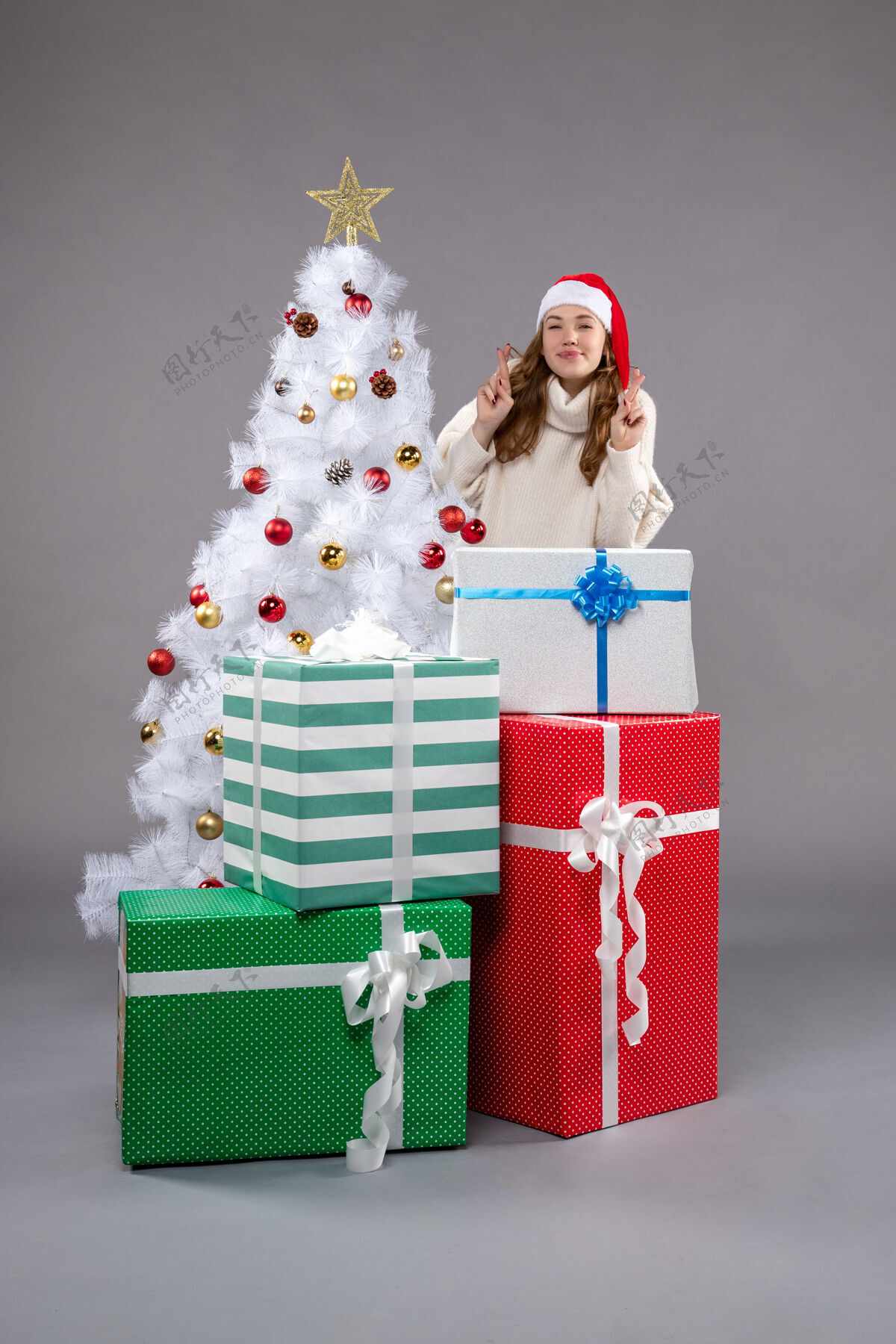 时尚年轻的女性在灰色的圣诞礼物周围圣诞圣诞树礼物