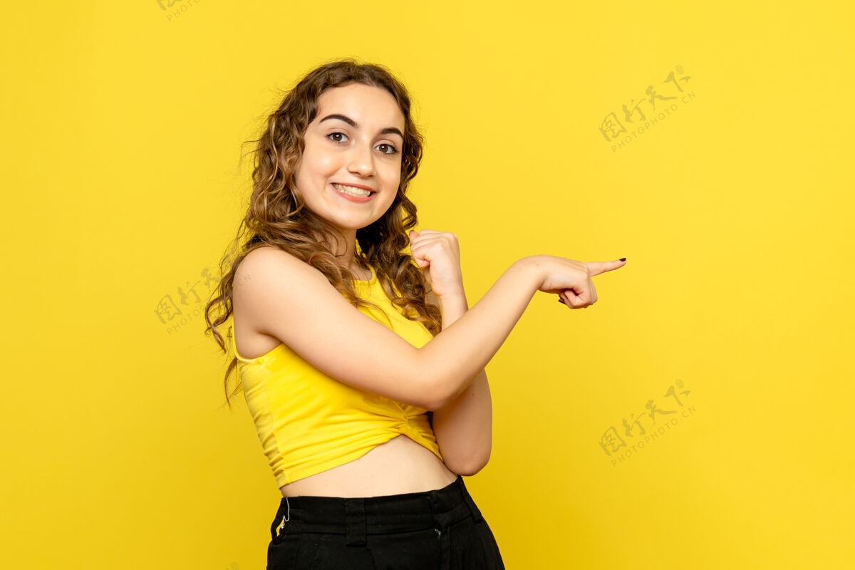 摆姿势正对着黄色墙上微笑的年轻女子发型女性人物