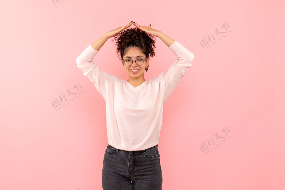 可爱年轻女子在粉红色墙上微笑的正面图快乐年轻人