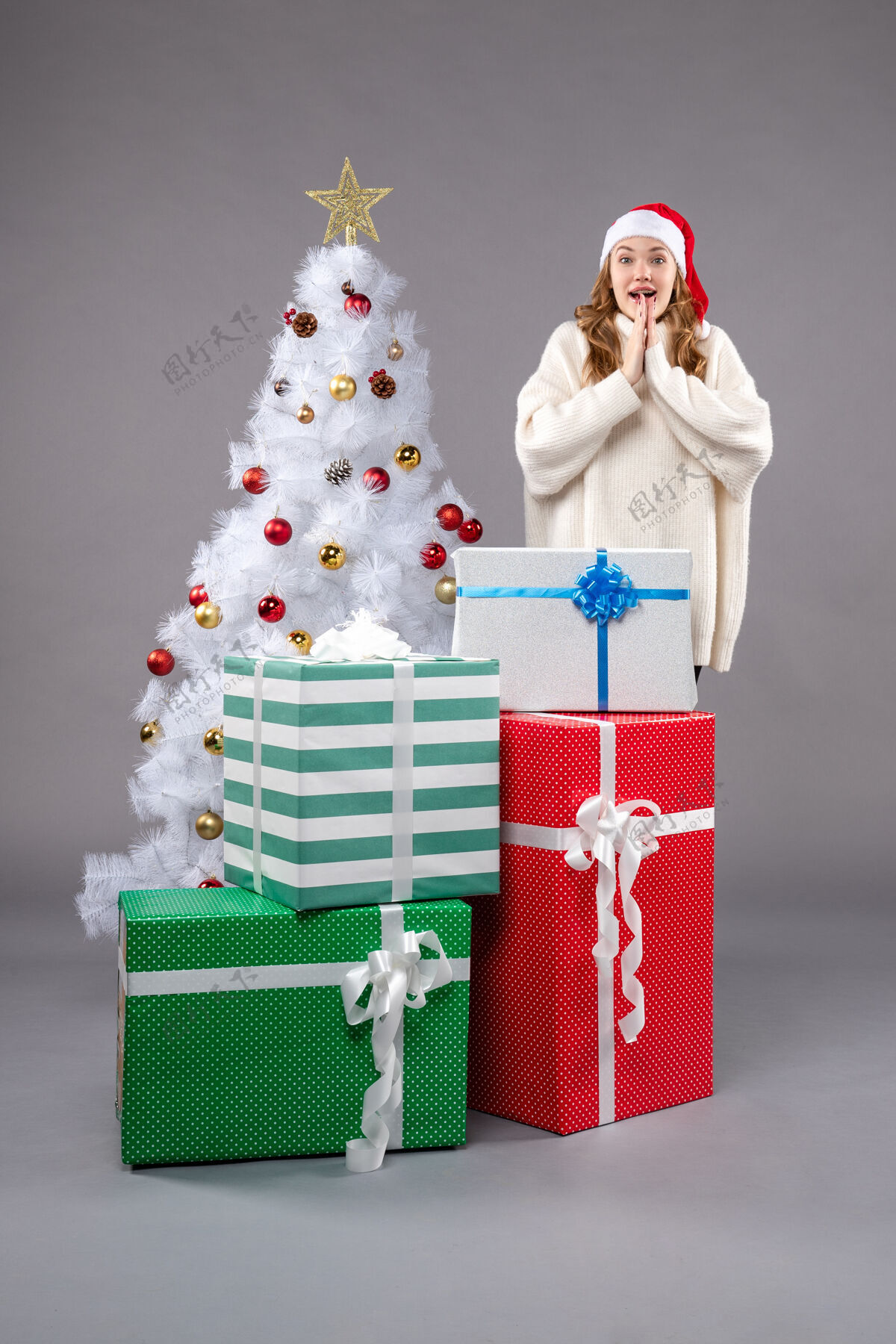 周围年轻的女人在灰色的地板上围着礼物圣诞树礼物圣诞树