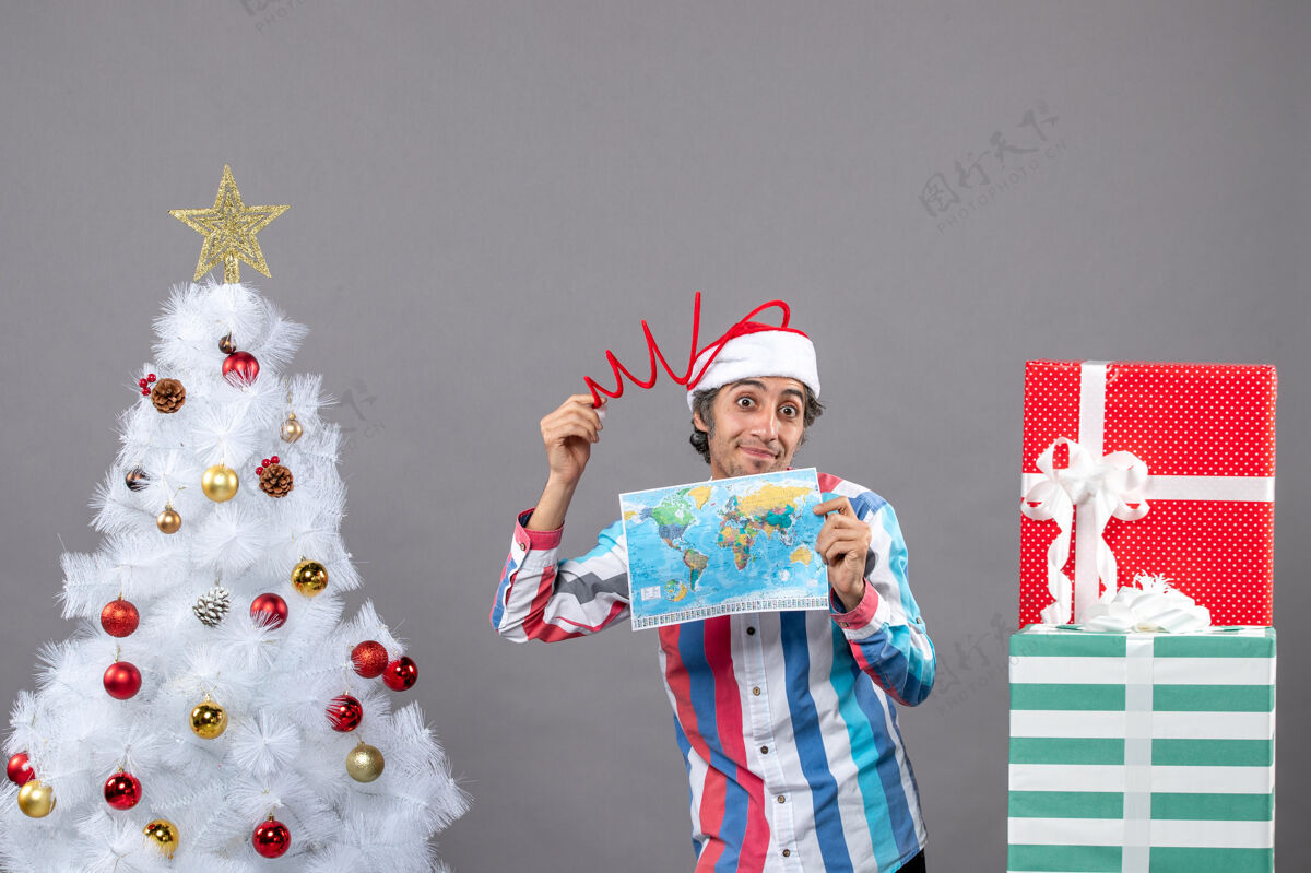 旅行者正面图满意的男子拿着螺旋弹簧圣诞帽拿着世界地图旅行春天圣诞