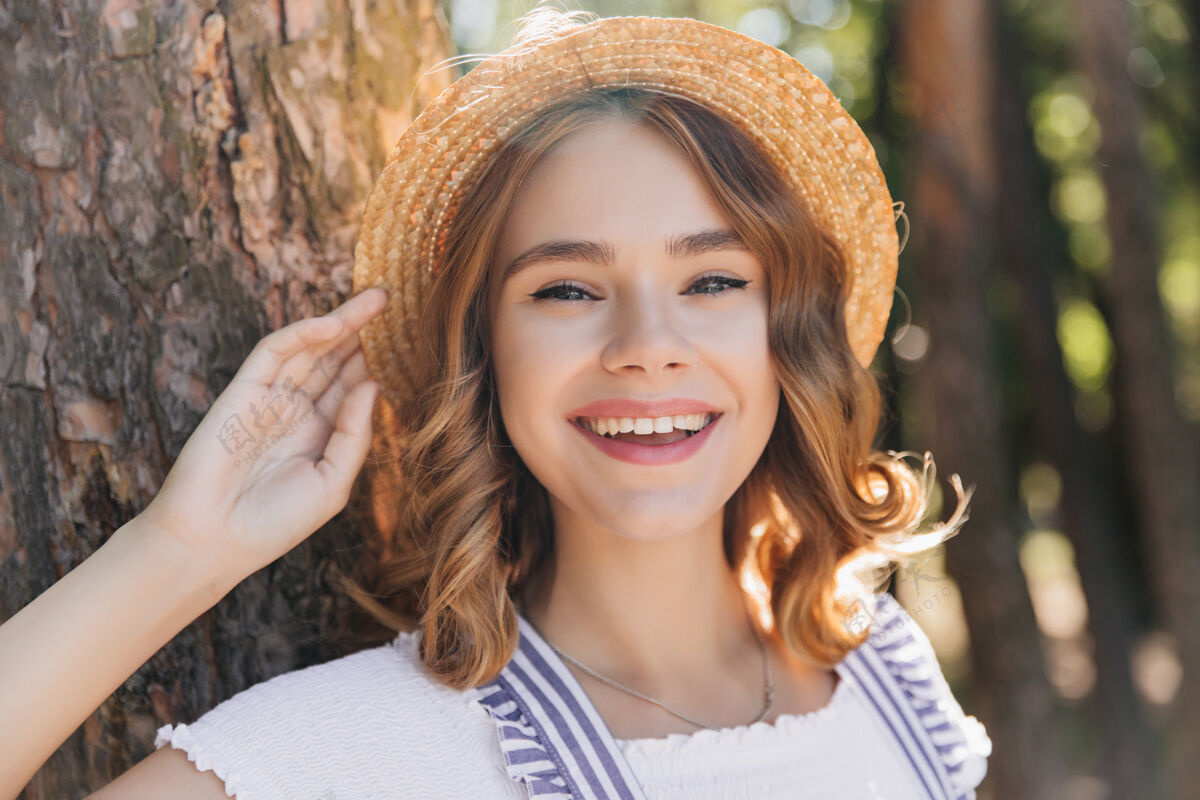 笑快乐的戴帽子的女模特在夏日微笑优雅的卷发女孩在森林里笑的户外镜头草户外自然