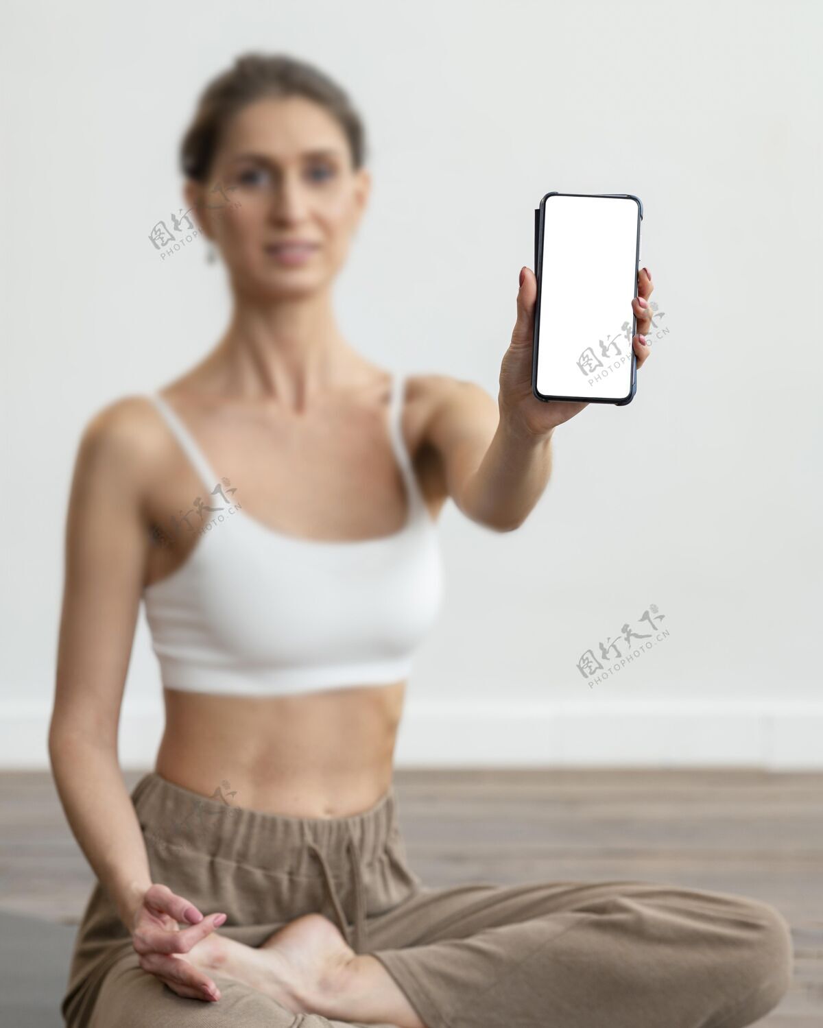 复制空间散焦的女人在家做瑜伽 拿着智能手机锻炼女人瑜伽