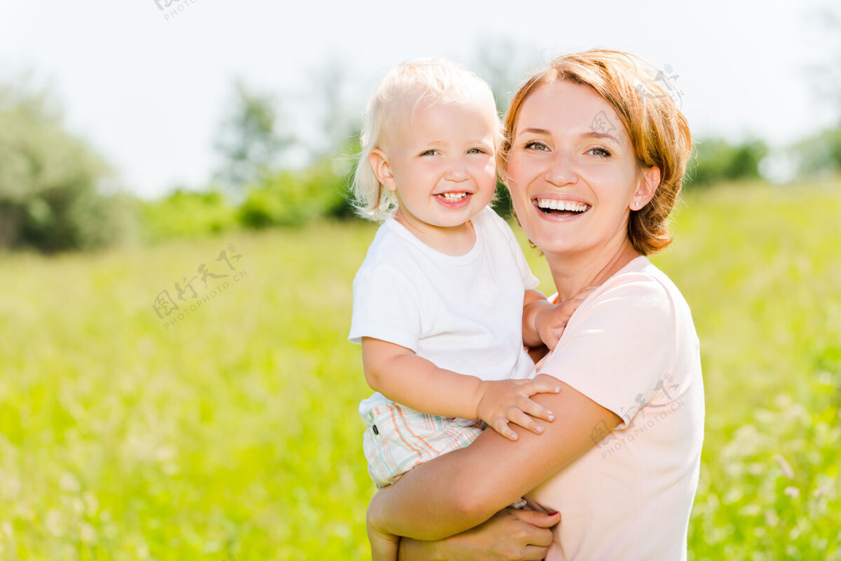 婴儿快乐的母亲和蹒跚学步的儿子在春天的草地户外写真快乐孩子自然