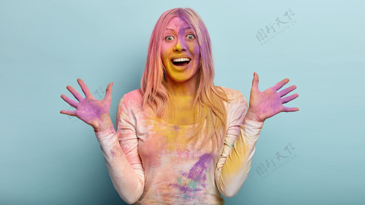 女人这张照片是一位高兴的欧洲妇女 她涂着紫色的手掌 舒展着双手 开心地笑着 情绪化地做着手势 在蓝色的墙壁上做模特 在印度的胡里节上玩得很开心外观节日快乐
