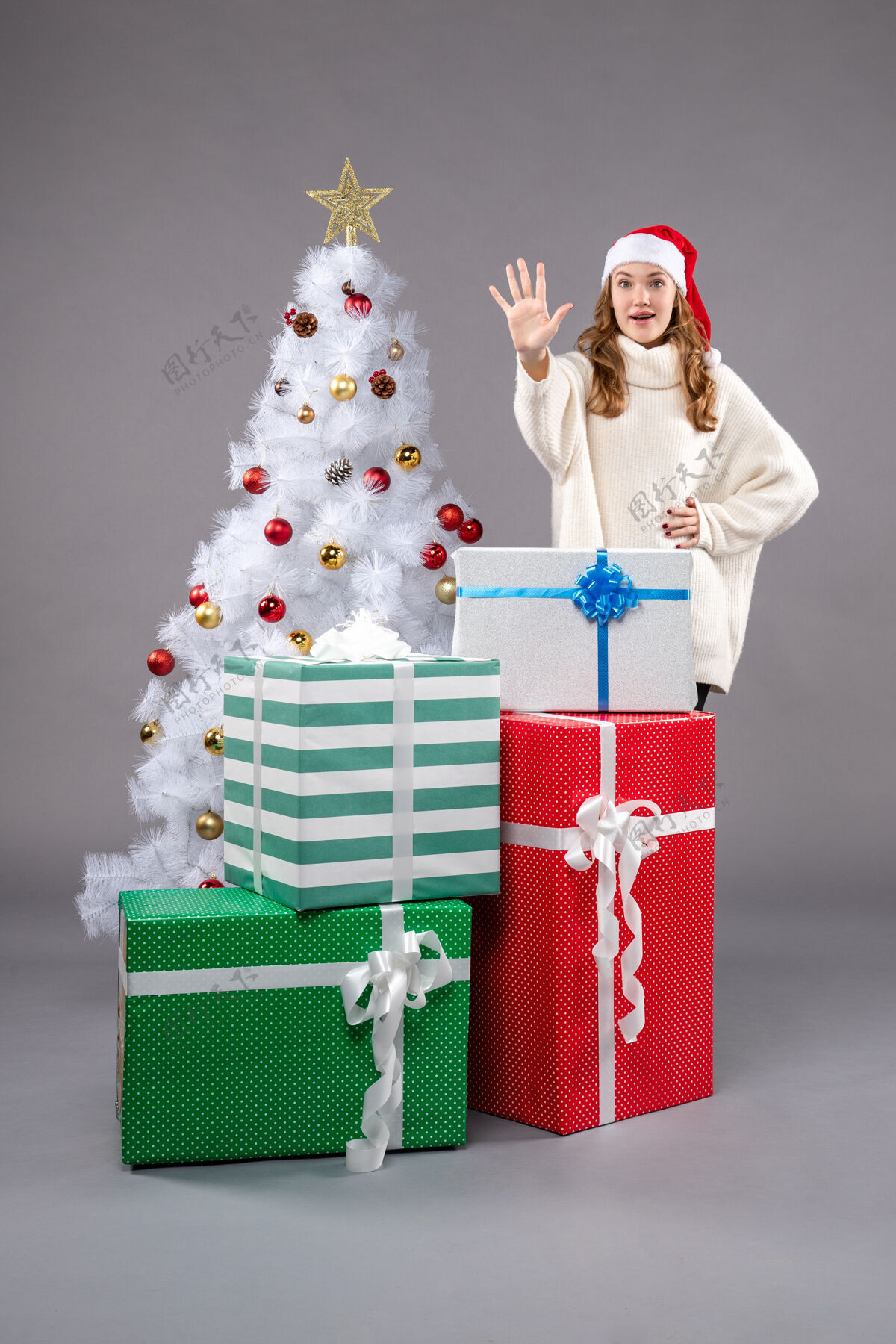 帽子年轻的女性在灰色的礼物圣诞老人礼物举行