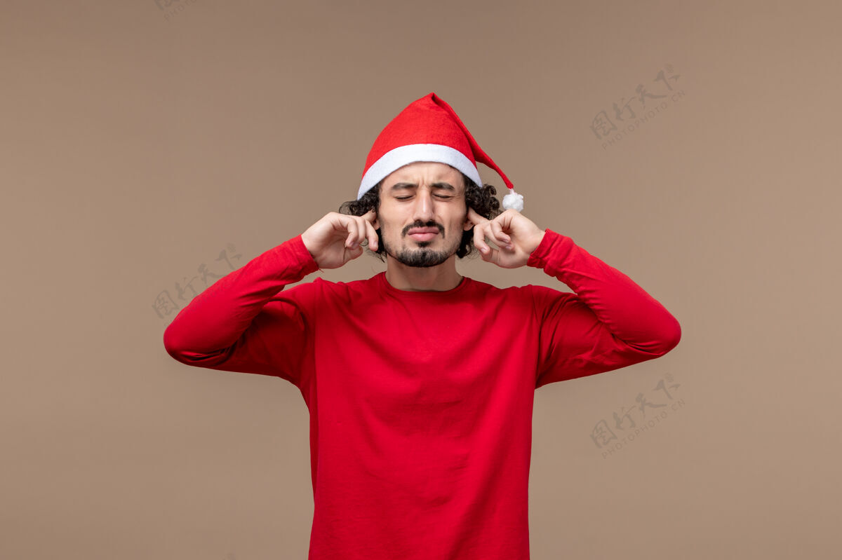 观点正面图：一个年轻人在圣诞假期的棕色背景上磕着耳朵男人肖像微笑