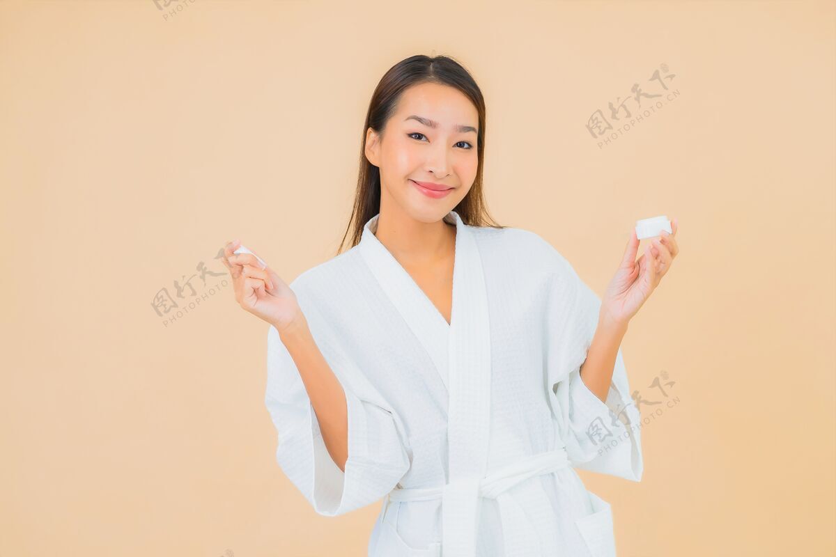 模特肖像美丽的亚洲年轻女子与瓶乳液和面霜米色纯净化妆女性