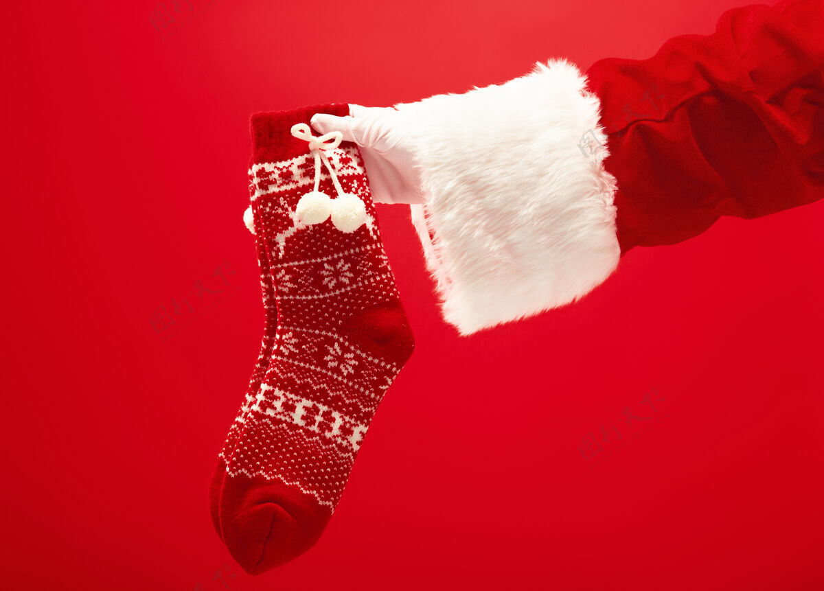 针织圣诞老人手里拿着一只红色的圣诞针织袜子欢乐传统礼物