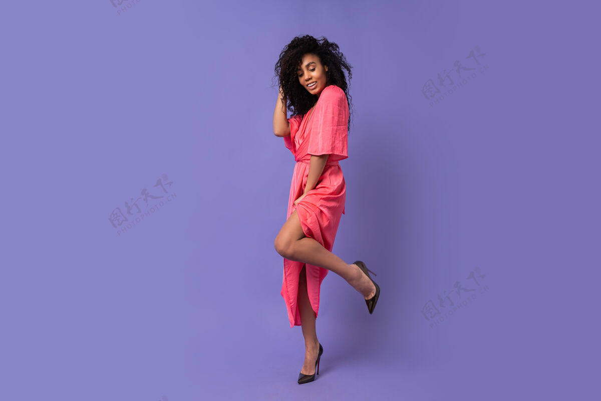 多民族一个快乐的女人 卷发在紫色的墙上摆着姿势穿着优雅的派对礼服春装全长肖像女性年轻