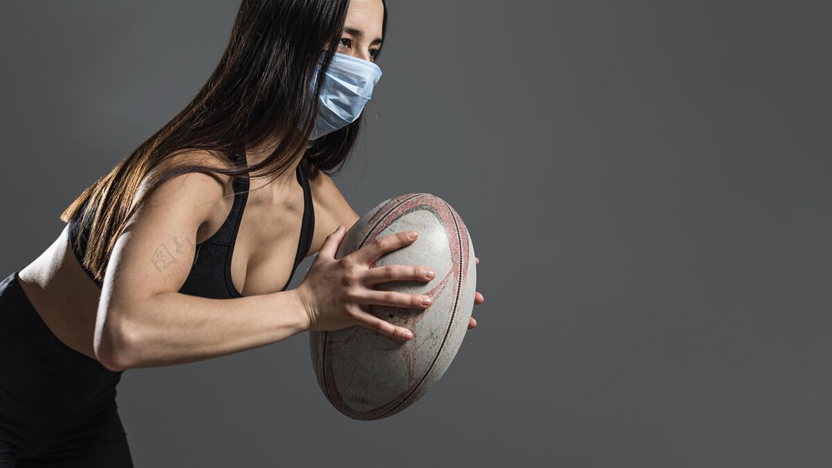 竞技戴着医用面罩手持球的女橄榄球运动员侧视图体育球橄榄球