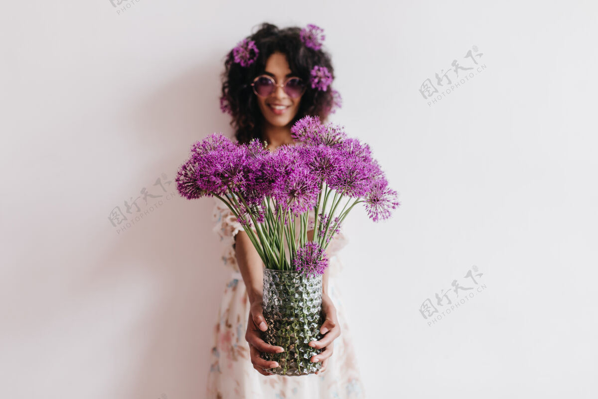 时尚美丽的非洲女士手持一瓶紫色的花浪漫的黑人年轻女子周末在家里玩的室内写真室内人成人