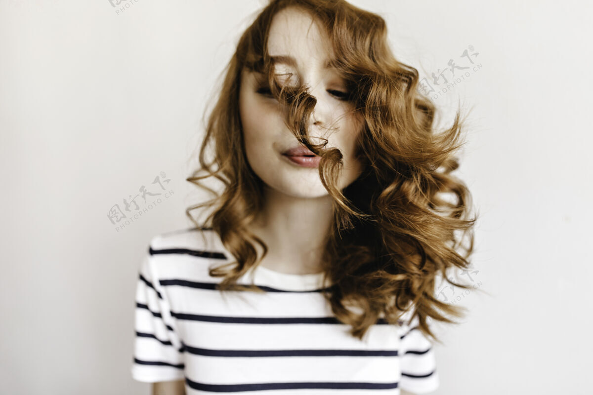 积极可爱的姜黄色女人吹着她的卷发快乐的白种女人红发可爱模特
