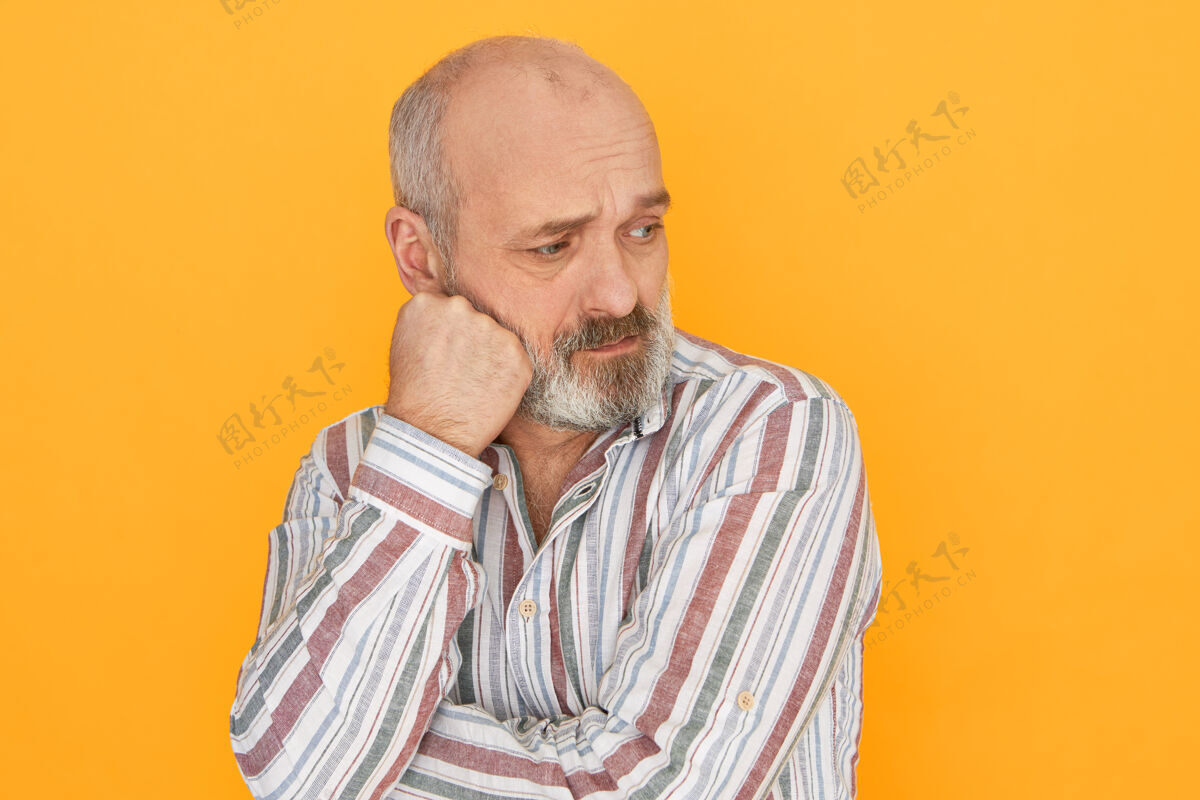 成人一个不幸的退休老人 留着灰白的胡子 秃顶 脸上挨着拳头年龄皱纹沉思