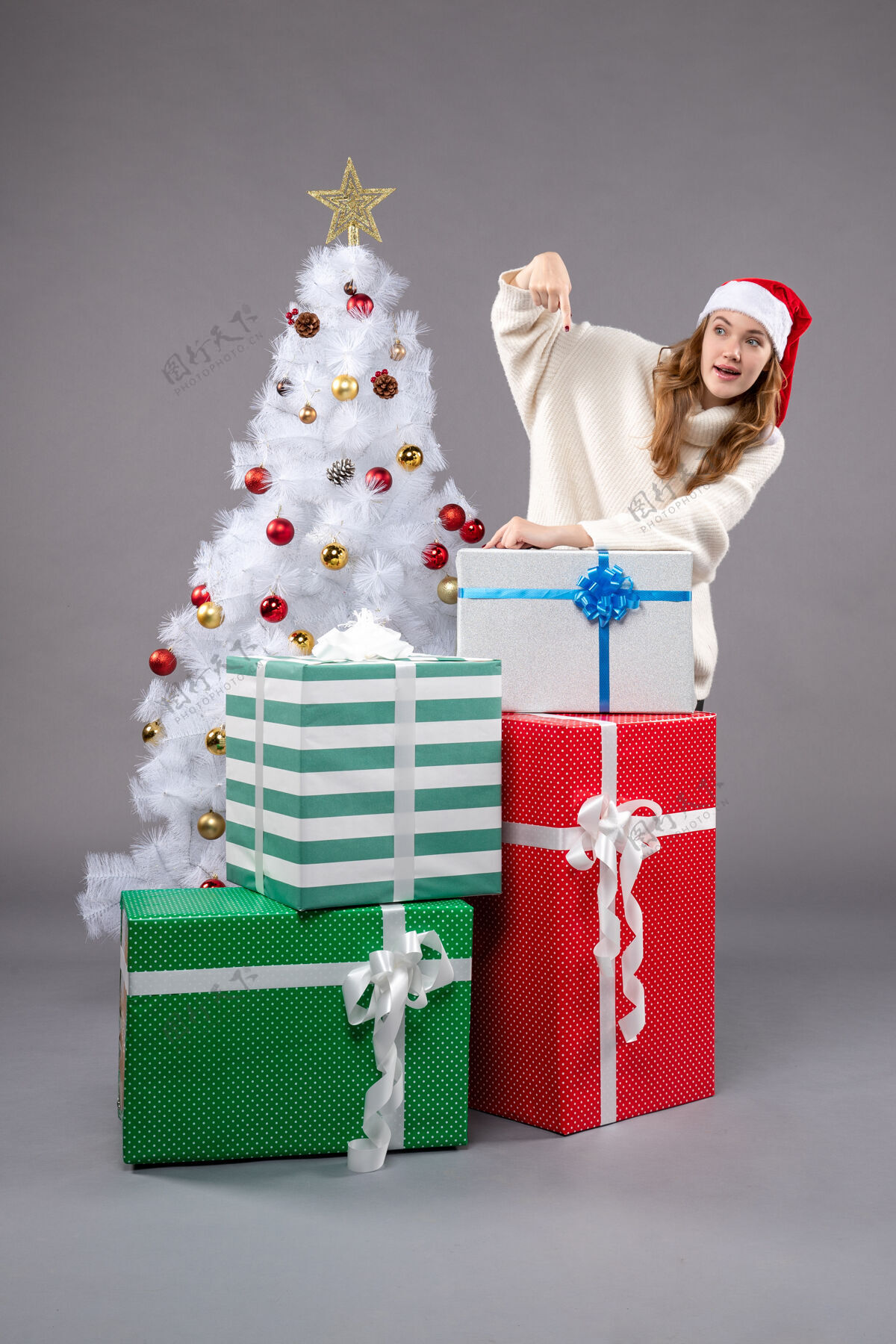 购物年轻的女性在灰色的圣诞礼物周围女性年轻女性圣诞