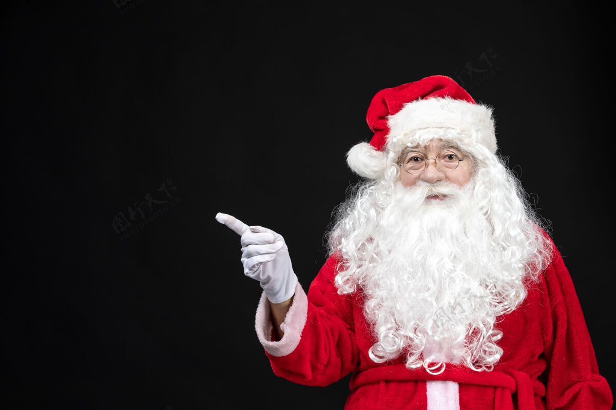 十二月圣诞老人穿着经典的红色套装 黑墙上留着白胡子的正面图人们圣诞前面
