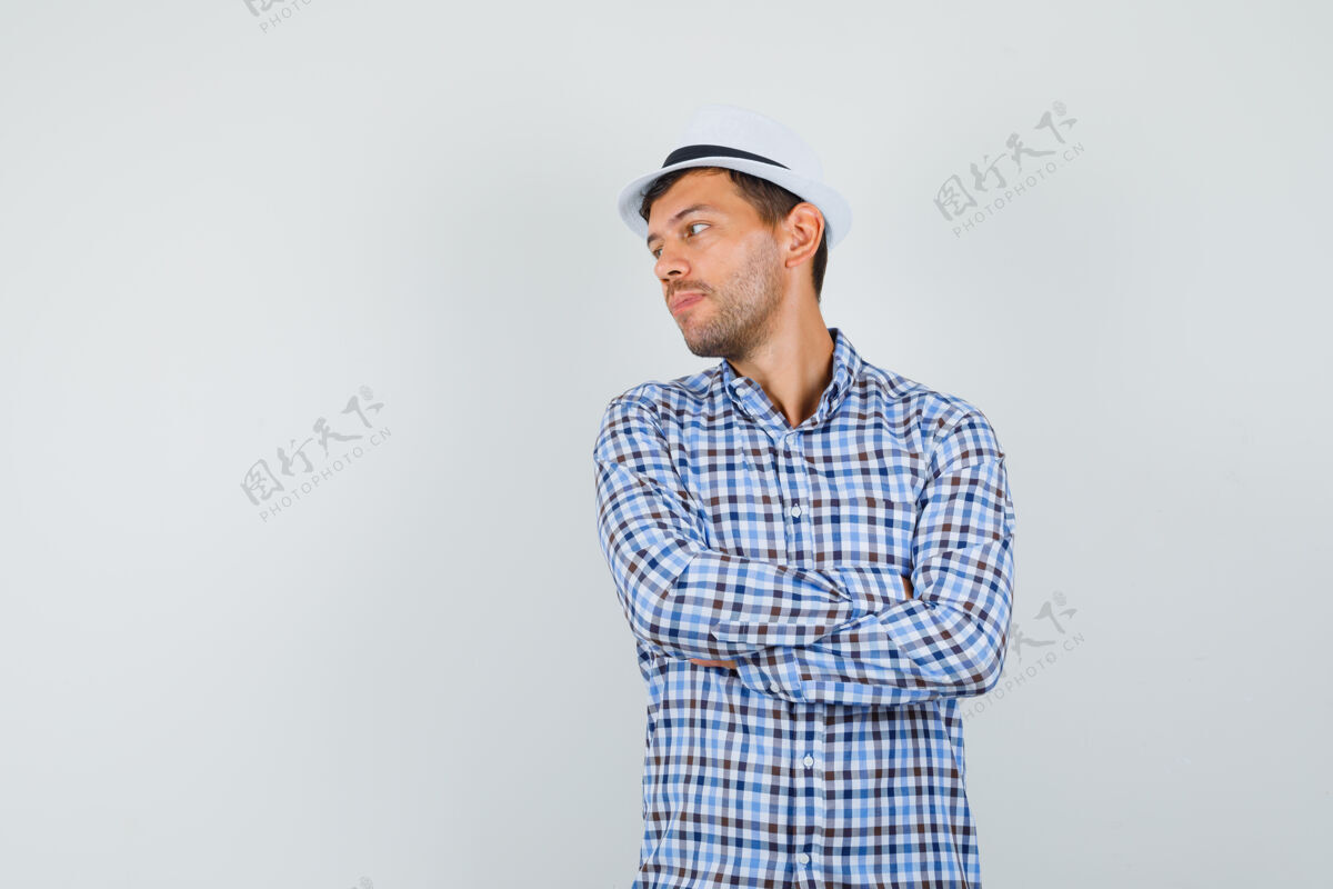 成人穿格子衬衫的年轻男子交叉双臂向一旁望去工作室年轻人物