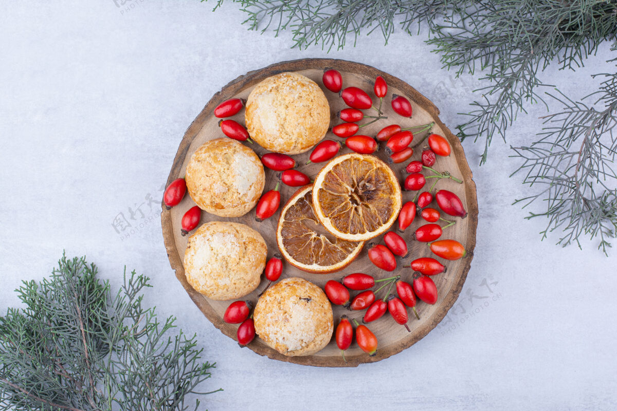 冬天美味的甜饼配橘子片和玫瑰果圣诞节玫瑰果云杉枝