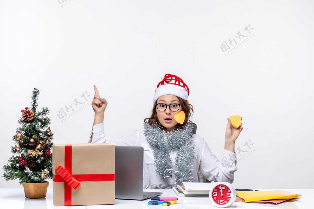 风景正面图：年轻的女工人坐在她的位置前 拿着白色背景上的贴纸白色坐着圣诞节