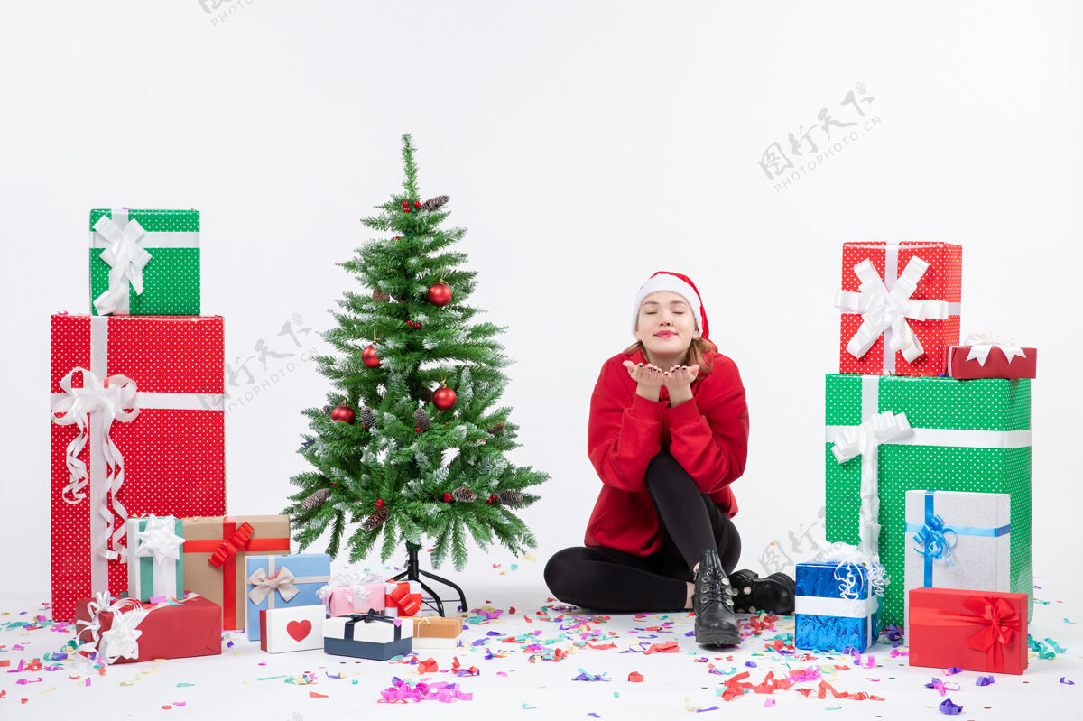 前面前视图年轻女子坐在周围的节日礼物发送在白墙上的飞吻礼物发送冬天